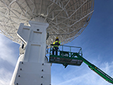 The underside of the VLBI antenna with a person in a lift near the top.